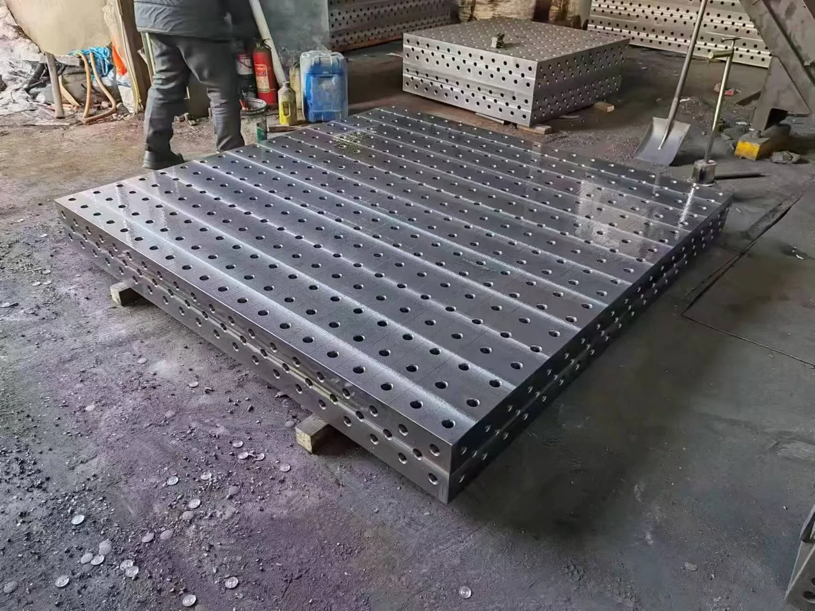 Large steel 3D welding table with machined hole grid in a workshop